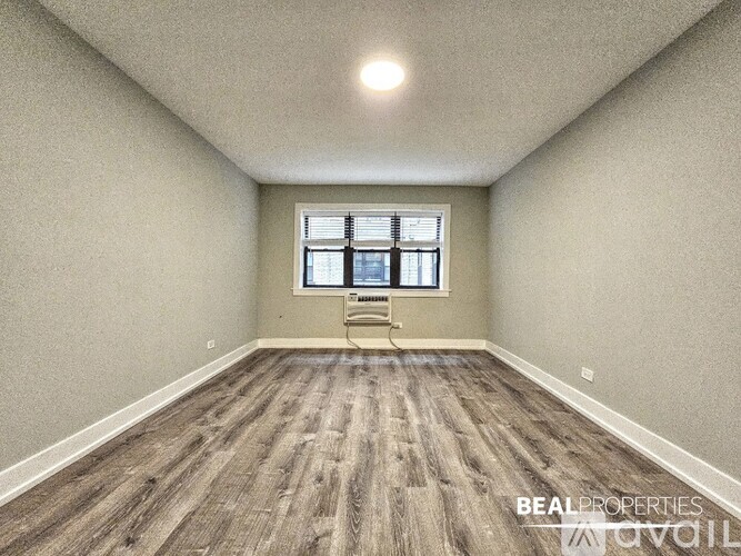 A spacious room with a window and a wooden floor.