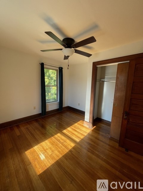A room with a ceiling fan and wooden flooring.