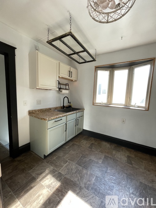 A kitchen with a sink and cabinets under a window.