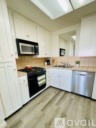 A kitchen with white cabinets and a black microwave above the stove.