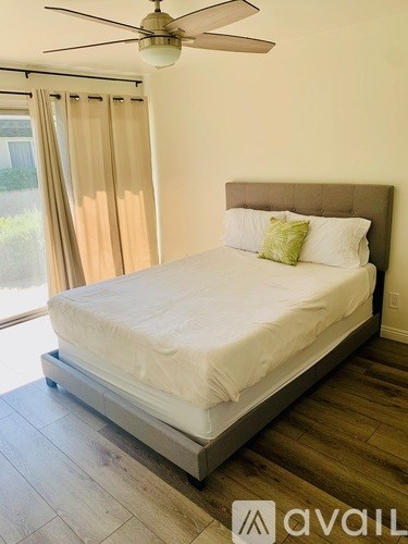 A bedroom with a bed, a ceiling fan, and a window with curtains.