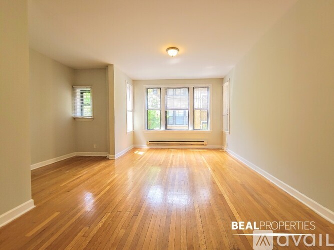 A room with wooden floors and a window with a view of trees.