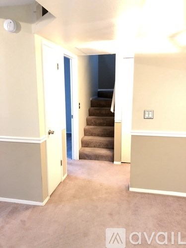 A hallway with a staircase leading to a bedroom.