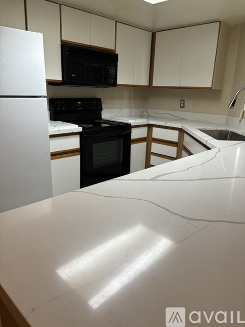 A kitchen with a white counter top and black appliances.
