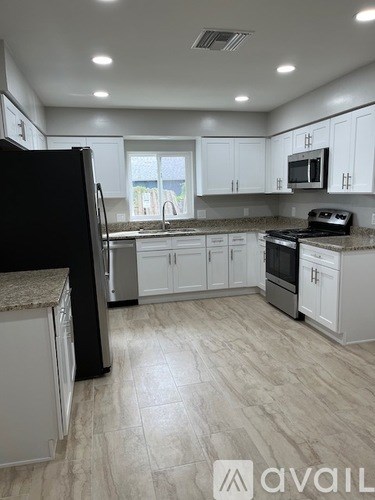 A kitchen with white cabinets and a black refrigerator.