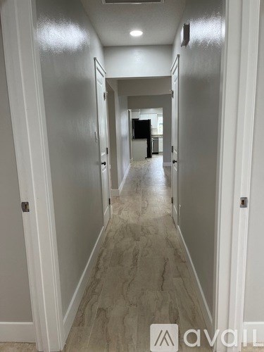A long hallway with marble floors and white walls.