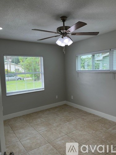 A room with a ceiling fan and two windows.