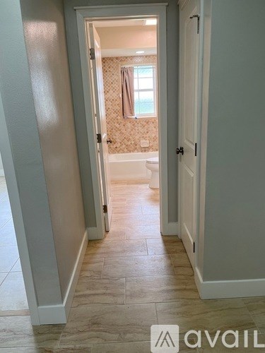 A hallway with a tile floor and a doorway leading to a bathroom.
