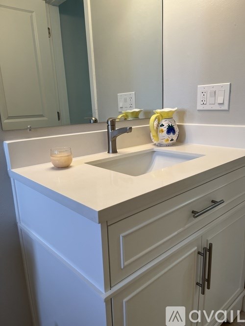 A white sink with a yellow and blue vase on top of it.