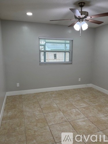 A room with a ceiling fan and a window with blinds.