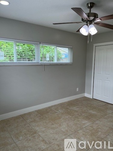 A room with a ceiling fan and a window with blinds.