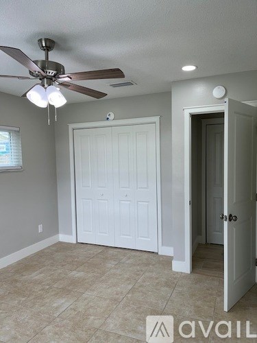 A room with a ceiling fan and a door.