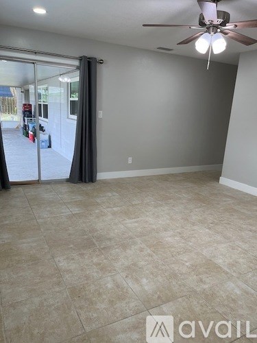 A room with a ceiling fan and sliding glass doors.