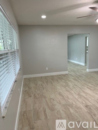 A room with a window covered by blinds and a wooden floor.