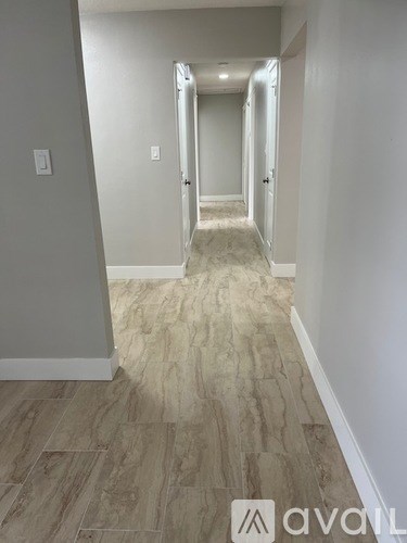 A hallway with a tiled floor and white walls.