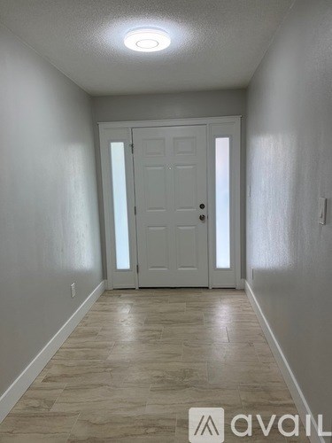 A hallway with a white door and tiled floor.