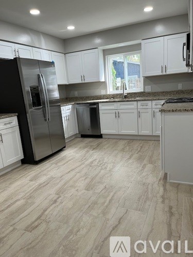 A kitchen with a black refrigerator and white cabinets.