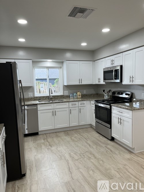 A kitchen with white cabinets and a black refrigerator.