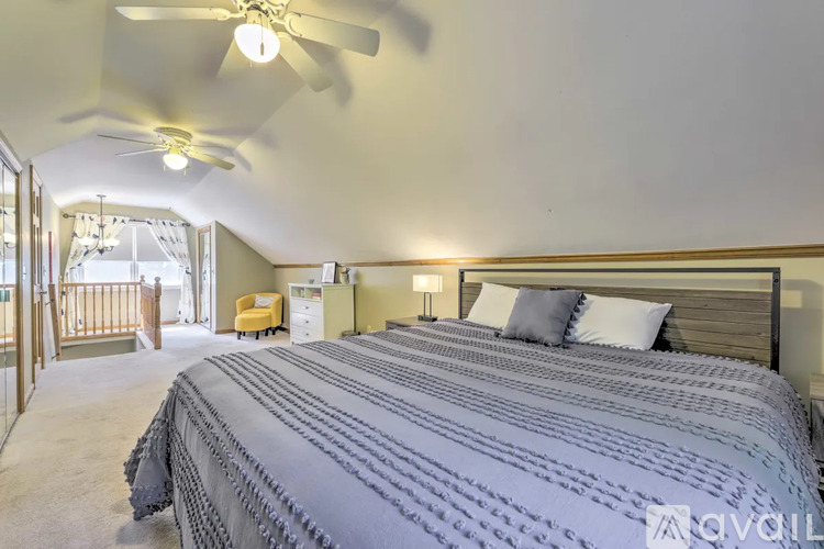 A bedroom with a large bed and a ceiling fan.
