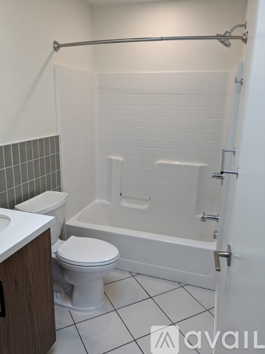 A white toilet sits next to a white bathtub in a bathroom.