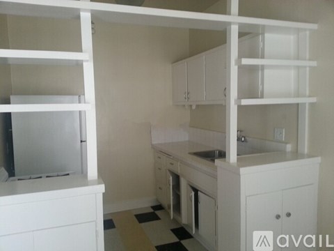 A kitchen with white cabinets and a checkered floor.