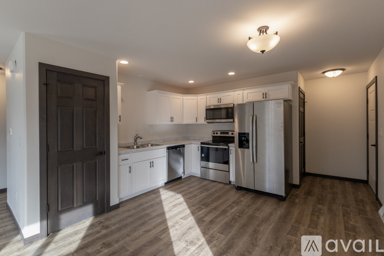 A modern kitchen with stainless steel appliances and wooden flooring.