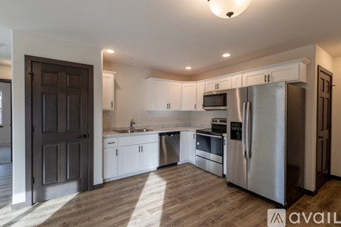 A kitchen with a refrigerator, sink, and cabinets.