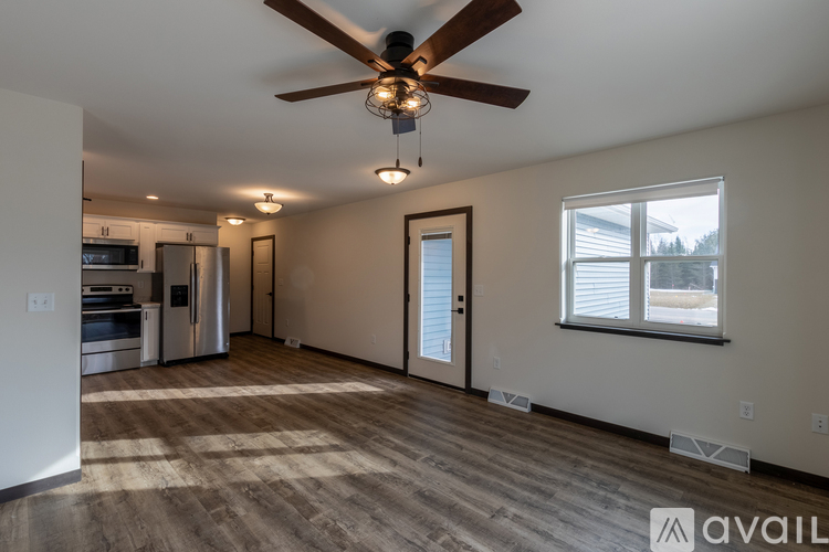 A spacious living room with a ceiling fan and a kitchen area in the background.
