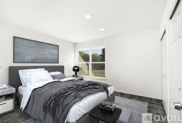 A modern bedroom with a large bed and a window overlooking a green landscape.