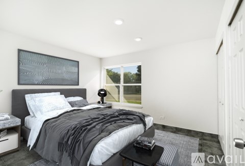 A modern bedroom with a large bed and a window overlooking a green landscape.