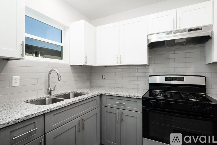 A kitchen with a black stove top oven and a window above the sink.