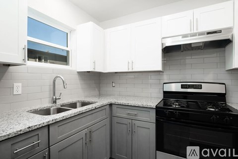 A kitchen with a black stove top oven and a window above the sink.