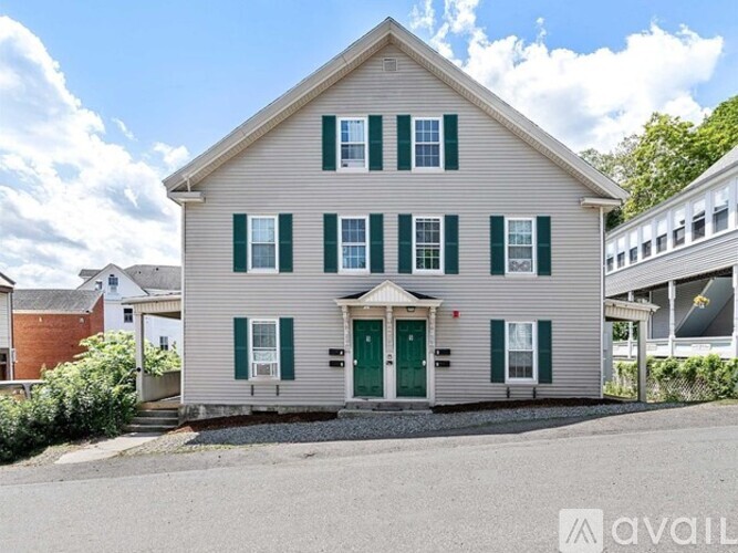 A house with a green door and shutters is for sale.