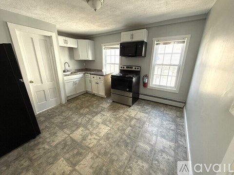 A kitchen with a black refrigerator, microwave, and stove.