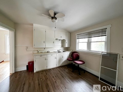A kitchen with white cabinets and a red chair.