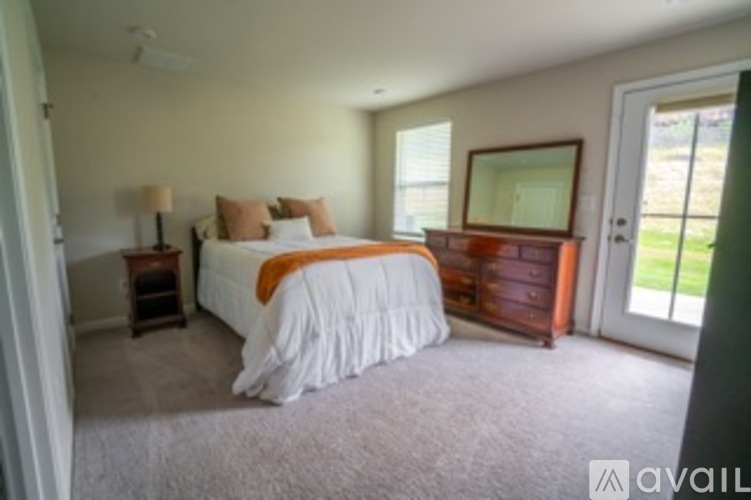 A bedroom with a bed, dresser, and window.