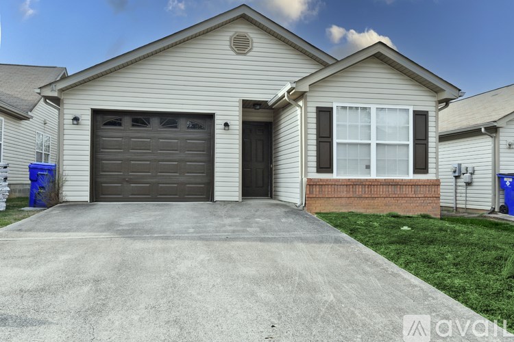 A house with a brown garage door and a brick pillar.