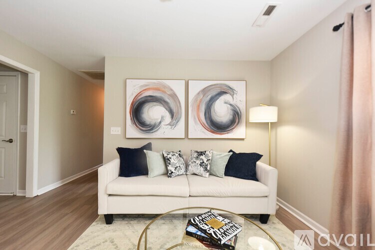 A living room with a white couch and two abstract paintings on the wall.