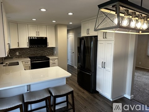 A kitchen with white cabinets and a black refrigerator.
