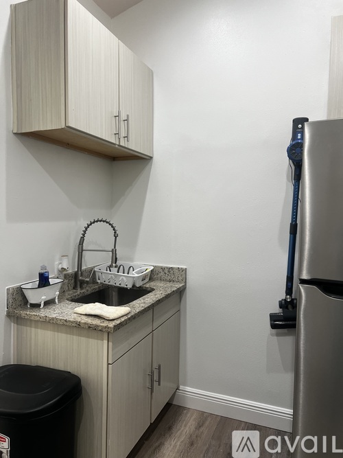 A kitchen with a sink, a refrigerator, and cabinets.