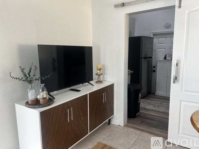 A white TV stand with a black TV on it and a plant on top.