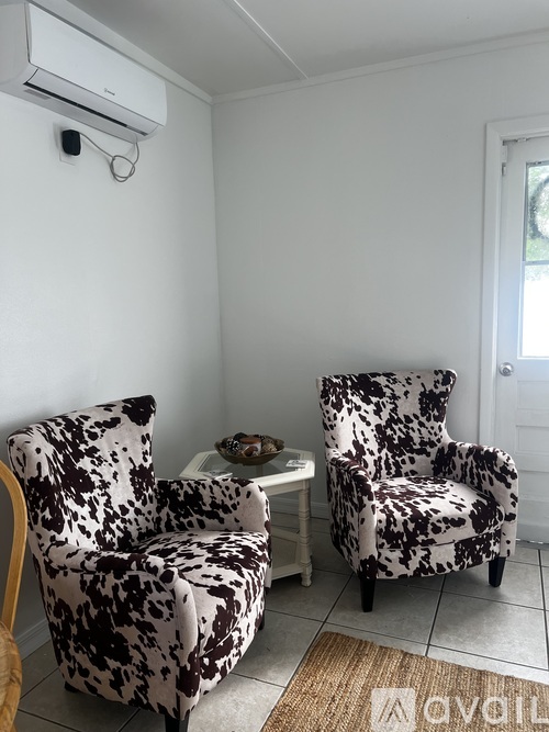 Two chairs with black and white patterned upholstery are in a room with a wall-mounted air conditioner.