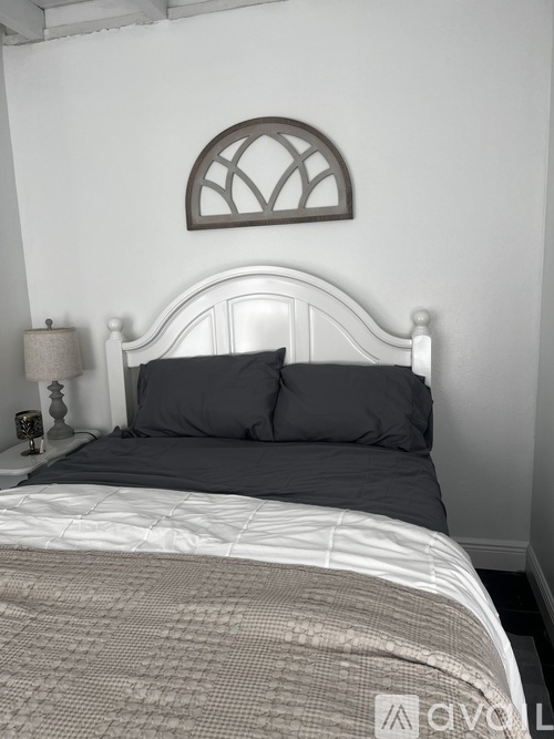 A bed with a white headboard and grey pillows is in the image.