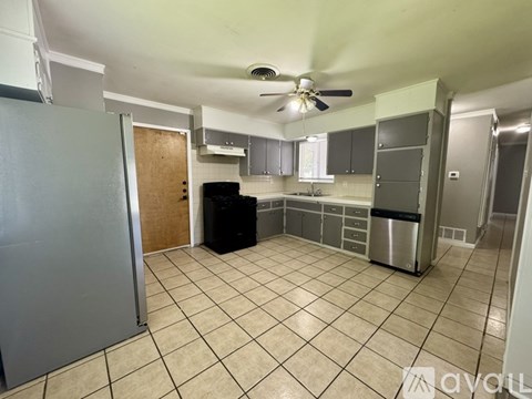 A kitchen with a black stove top oven and a tiled floor.