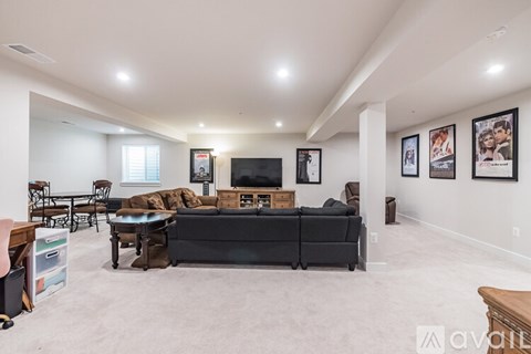 A living room with a black couch and a flat screen TV mounted on the wall.