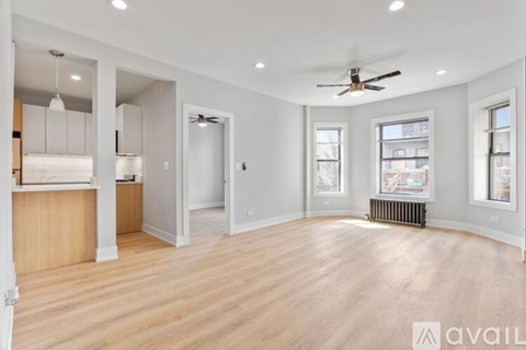 A spacious room with wooden floors and a ceiling fan.