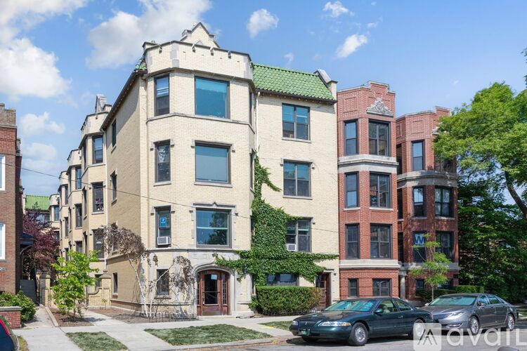 A row of apartment buildings with cars parked in front.