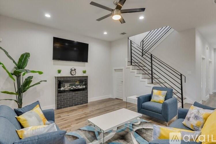 A living room with a blue couch, a white coffee table, and a TV mounted on the wall.