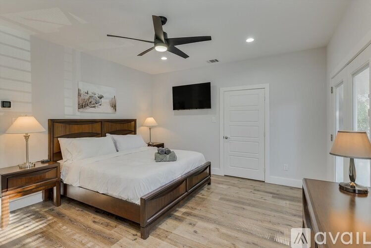 A bedroom with a large bed, a ceiling fan, and a painting on the wall.