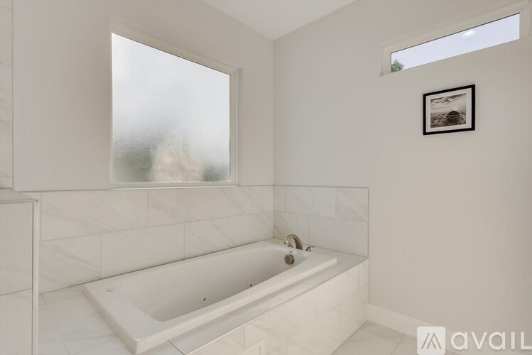 A white bathroom with a tub and a window.